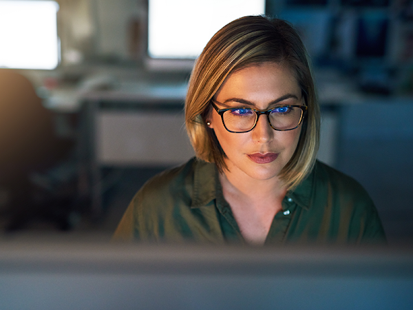 A woman sits at a desk looking at her computer.