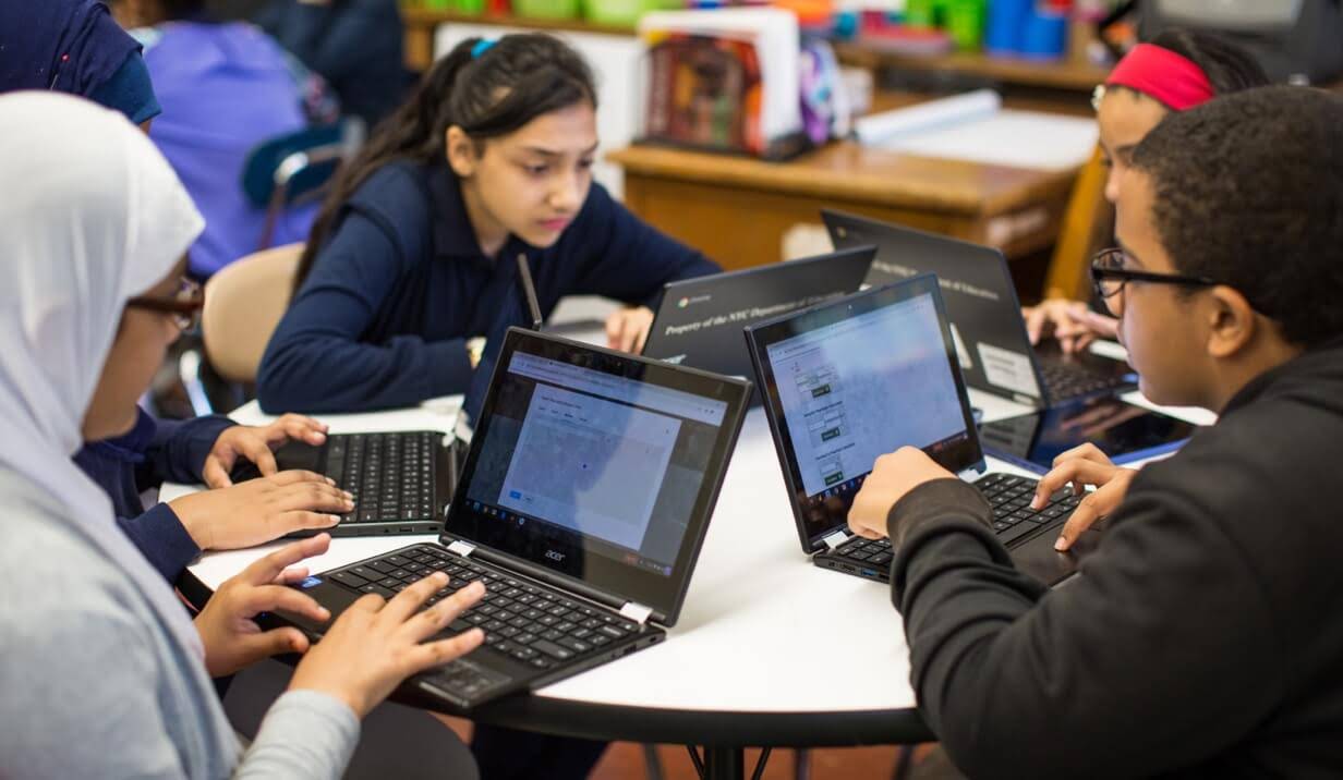 Vier Schüler einer nahöstlichen Schule arbeiten zusammen an einem runden Tisch