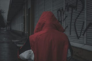 A dubious person in a red hoodie walking away.