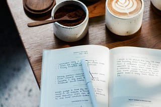 A journal and coffee with coffee beans on a vintage table