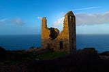 A cornish granite ruin by the sea glows in the dawn.