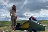 A hairy topless hiker shows ribs and abs beside his tent.