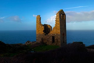 A cornish granite ruin by the sea glows in the dawn.