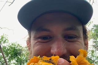 A hiker smiles holding a hoard of golden chanterelles