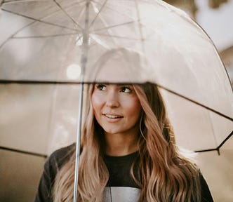 A young woman looking under an umbrella.