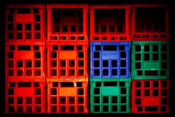 A wall of red, blue and green plastic crates