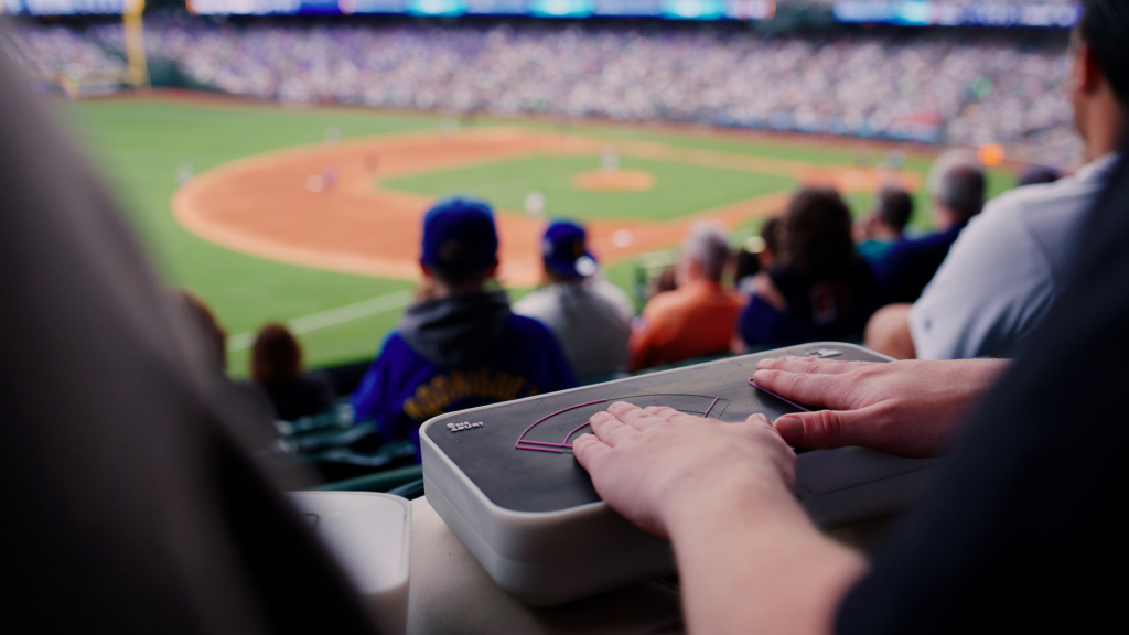 Image of a fan using the device at a baseball game.