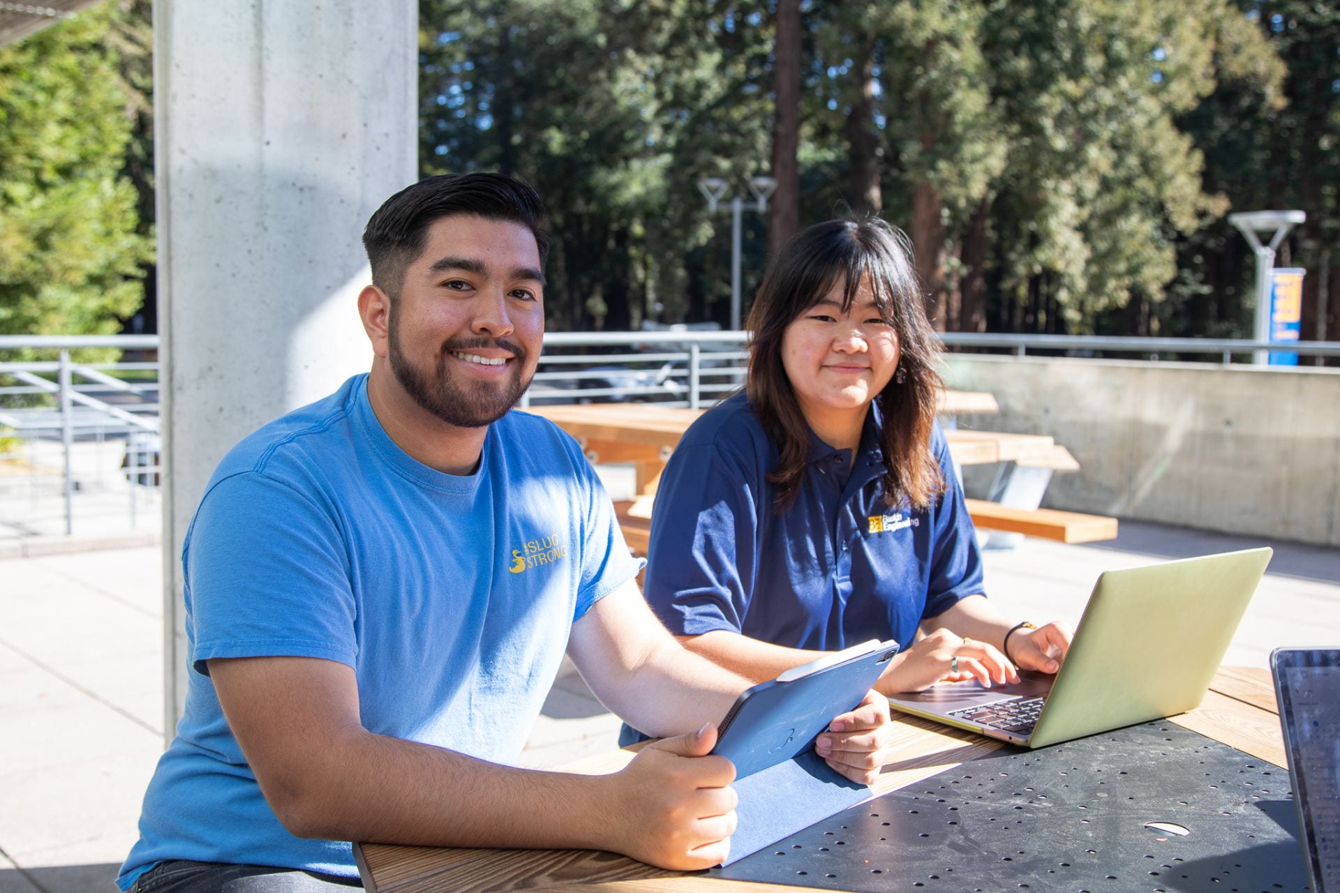 Two students looking at their computers and smiling