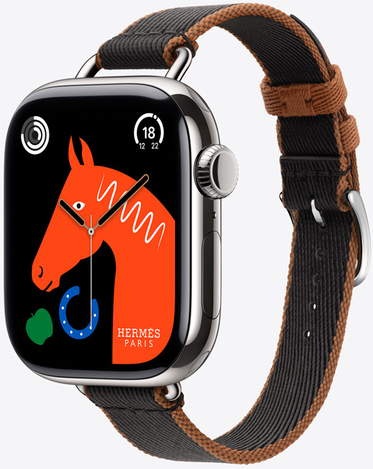 Angled view of the new Attelage Twill Jump Single Tour band in Noir/Gold (black with gold trim) with the 'Lucky Horse' watch face featuring an orange horse's head, a green apple, and a blue horseshoe.