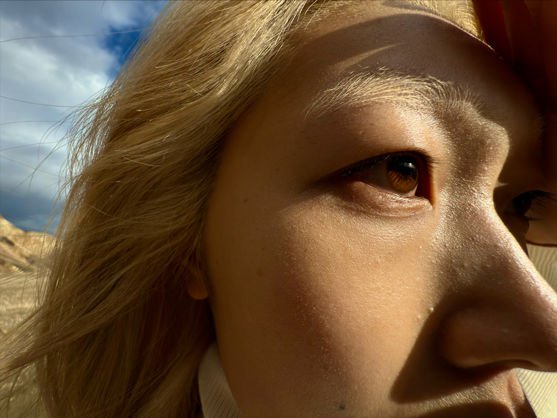 Close-up of a woman with windblown hair demonstrating the 0.5x Macro setting