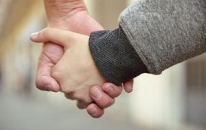 an adult is holding a child's hand. blurred background.