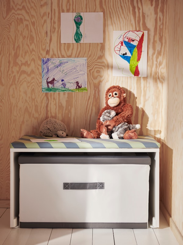 A white SMÅSTAD bench with a white/grey JÄTTEBJÖRN box with lid underneath and a DJUNGELSKOG soft toy orangutan on top.