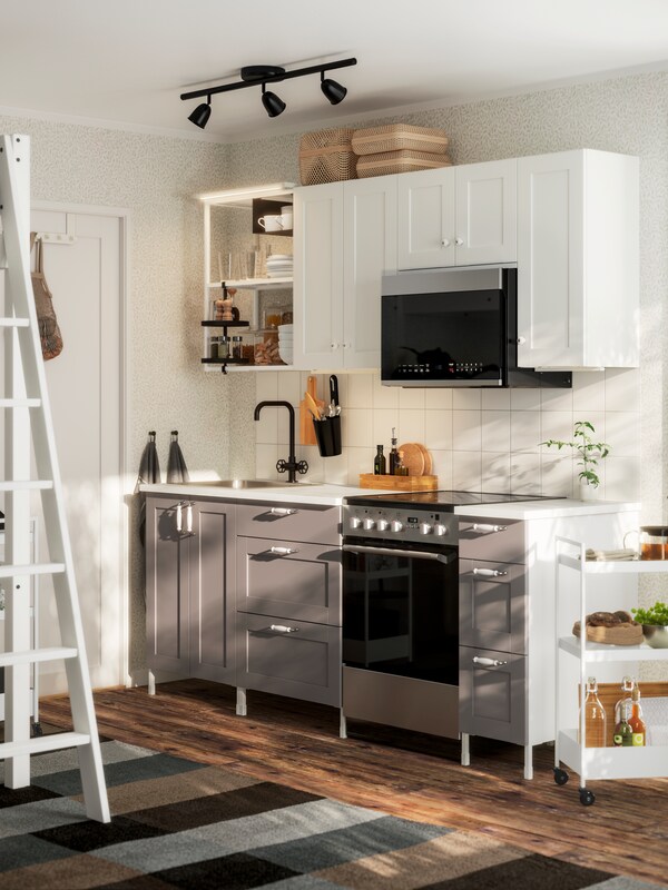 A kitchen with a traditional look and feel with wooden floors and boxes and ENHET kitchen with white and gray fronts.