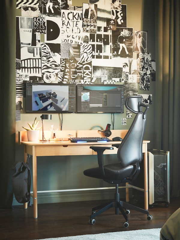 A green-themed room with a RIDSPÖ oak-veneer desk by dark-green ROSENMANDEL curtains, opened to reveal screens and wall art.