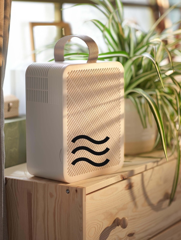 A white air purifier sitting on a dresser and a breeze wind icon showing on top of the image.