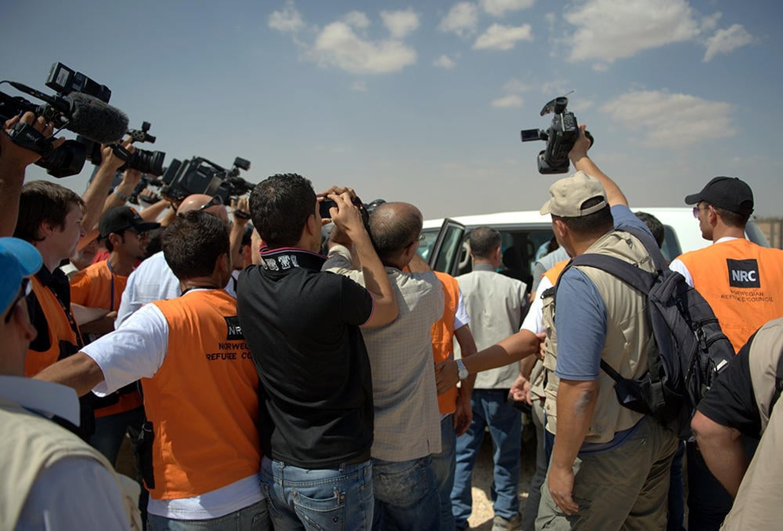 Journalists crowding around a car.