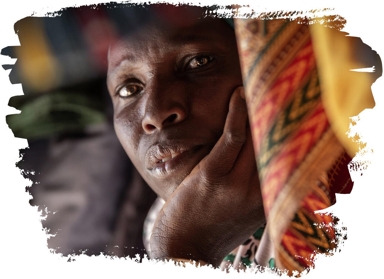 Portrait of a woman resting her head in her hand, surrounded by colourful fabric.