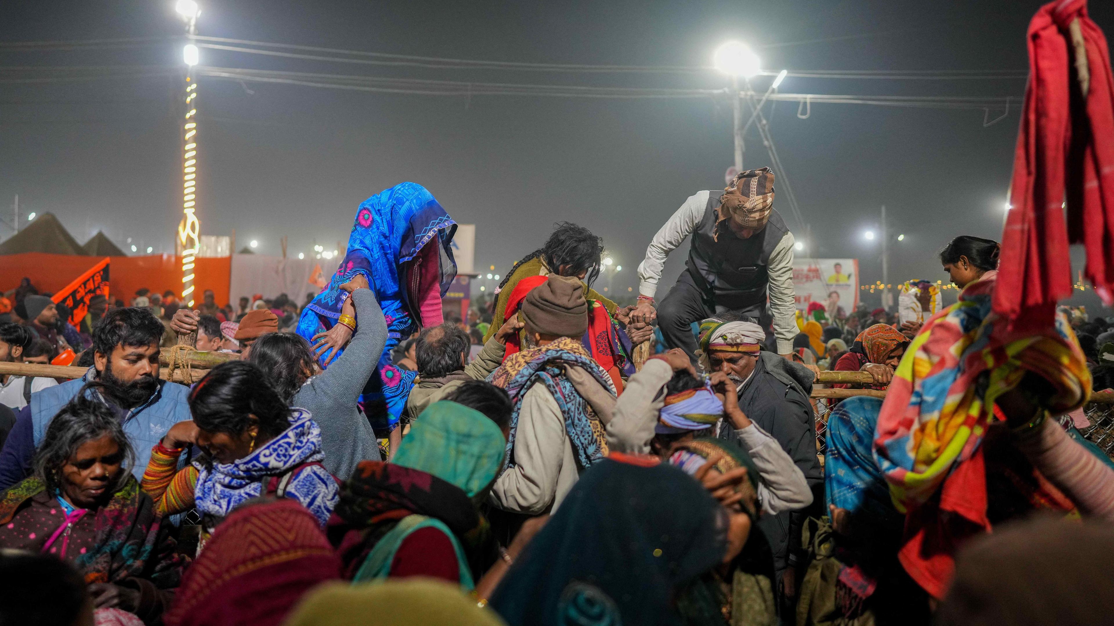 Hindu-Pilger versuchen, eine Barrikade zu überqueren, um ein heiliges Bad in der Nähe des Ortes zu nehmen, an dem es während des Maha Kumbh Mela-Festivals in Prayagraj, Indien, am 29. Januar 2025 zu einer Massenpanik kam.